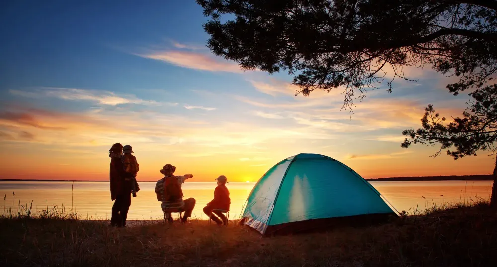 Family of four camping at sunset